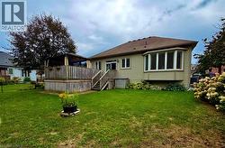 Expansive backyard featuring a large wood-finish deck with privacy fencing, dual-level access, and a bay window on the home's exterior - 