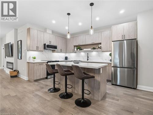 Kitchen with stainless steel appliances, light wood finish cabinets, a center island, a breakfast bar, and pendant lighting - 230 Knoll Street, Port Colborne, ON 