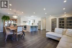 Open-concept living area with dark wood-finish flooring, recessed lighting, and a chandelier - 