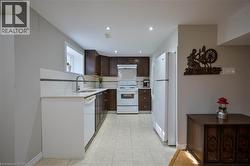 Kitchen featuring dark wood-finish cabinetry, white appliances, light-toned countertop, and recessed lighting - 