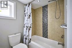 Tub/shower combination with tile surround featuring a mosaic accent, recessed lighting, and a window - 