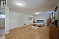 Spacious room featuring wood-finish flooring, white walls, and a window providing natural light - 