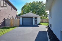 Detached garage with a shingled roof and a paved driveway - 