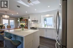 Kitchen featuring a waterfall island with stone countertop, recessed lighting, wood-finish flooring, white cabinetry, and stainless steel appliances - 