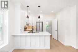 Contemporary kitchen with white shaker cabinetry, stainless steel appliances, a marble-finish countertop, and a decorative tile backsplash - 