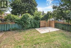 Backyard featuring a concrete pad, a wood privacy screen, and a green picket fence - 