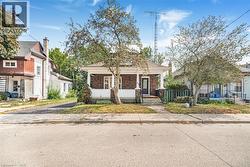 Brick facade with white siding, covered front porch, and mature front yard trees - 