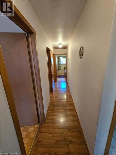 Hardwood flooring throughout a long corridor with multiple doorways and a ceiling-mounted light fixture - 410 Lakeview Drive, Waterloo, ON 