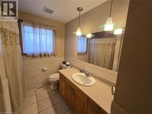 Integrated vanity with an oval basin sink and wood-finish cabinetry, tile flooring, and a large wall-mounted mirror - 410 Lakeview Drive, Waterloo, ON 