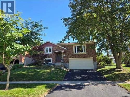Brick exterior, single garage, paved driveway, mature trees, and a front yard with established landscaping - 410 Lakeview Drive, Waterloo, ON 