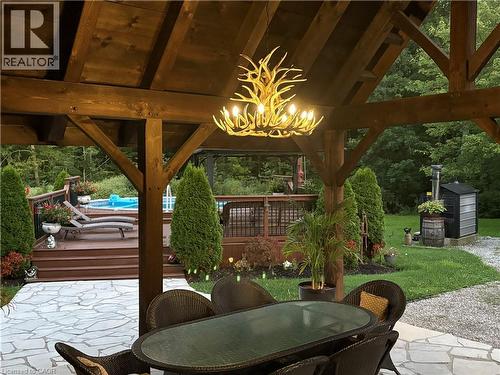 Expansive covered patio with exposed wood beams and a unique chandelier - 664 Concession 3 Road, Fisherville, ON 