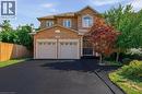 Multi-story brick exterior featuring a double-car garage, asphalt driveway, arched window detailing, and landscaped yard - 2381 Grand Oak Trail, Oakville, ON 