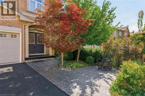 Brick exterior facade with stone trim, double-door entrance, stone-patterned concrete walkway, and paved driveway - 2381 Grand Oak Trail, Oakville, ON 