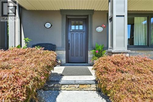 Stone steps leading to a dark wood entry door with glass panels, flanked by substantial landscaping - 2209 Ghent Avenue, Burlington, ON 