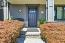 Stone steps leading to a dark wood entry door with glass panels, flanked by substantial landscaping - 2209 Ghent Avenue, Burlington, ON 