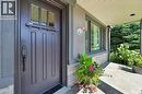 Recessed entryway featuring a paneled door with transom windows, a stone accent wall, and a covered porch with recessed lighting - 2209 Ghent Avenue, Burlington, ON 