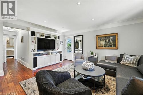 Hardwood-finish flooring, built-in entertainment center with shelving and cabinetry, recessed ceiling lighting, crown molding, and a paneled door with glass inserts - 2209 Ghent Avenue, Burlington, ON 
