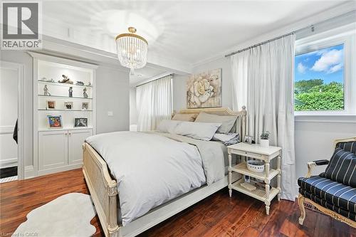 Built-in cabinetry with glass shelving, wood-finish flooring, and a decorative overhead light fixture - 2209 Ghent Avenue, Burlington, ON 