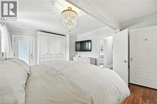 Decorative chandelier, white built-in cabinetry, wood-finish flooring, white paneled doors, and ceiling beam - 2209 Ghent Avenue, Burlington, ON 