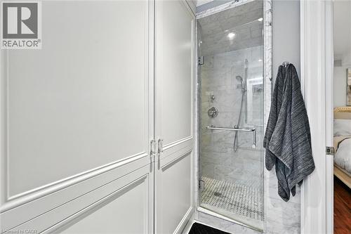 Glass-enclosed shower with marble-finish tile surround, fixed and handheld showerheads, and a tiled shower pan - 2209 Ghent Avenue, Burlington, ON 