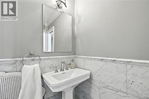 Pedestal sink with polished chrome fixtures, framed mirror, and marble wainscoting - 2209 Ghent Avenue, Burlington, ON 