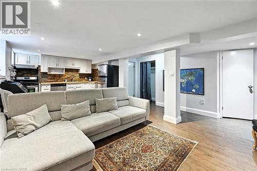 Open-concept living area with wood-finish flooring, recessed lighting, and a full kitchen featuring light cabinetry, stainless steel appliances, and a tiled backsplash - 2209 Ghent Avenue, Burlington, ON 