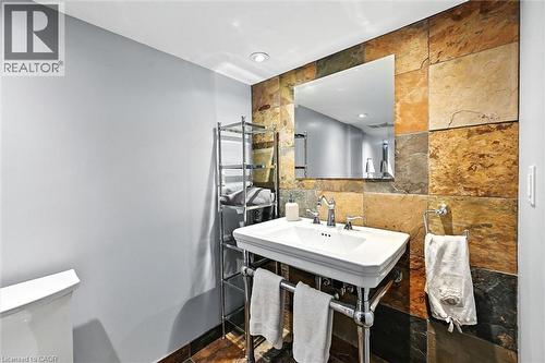 Wall-mounted rectangular mirror above a pedestal sink with a chrome faucet - 2209 Ghent Avenue, Burlington, ON 