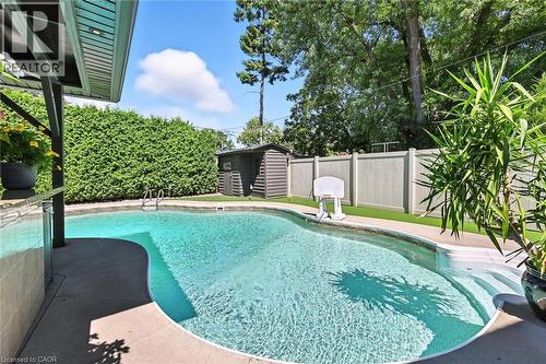 Swimming pool with integrated steps, concrete surround, privacy hedging, and an artificial turf area - 2209 Ghent Avenue, Burlington, ON 