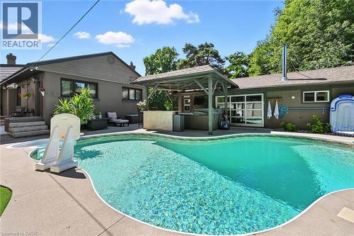 Curved swimming pool with integrated spa and surrounding concrete decking - 2209 Ghent Avenue, Burlington, ON 