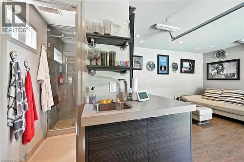 Wet bar with a single basin sink, floating shelving, and dark wood-finish cabinetry - 2209 Ghent Avenue, Burlington, ON 