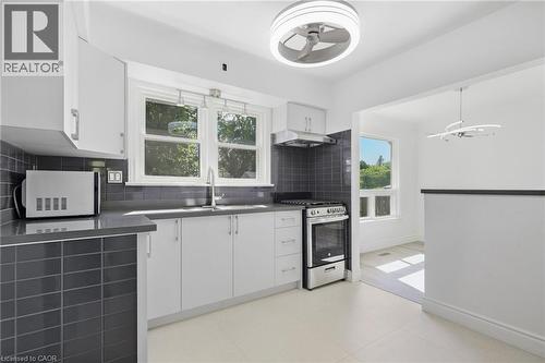 Kitchen featuring white cabinetry, grey subway tile backsplash, stainless steel appliances, and a modern ceiling fan - 49 Beverly Crescent, Welland, ON 