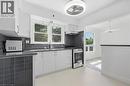 Kitchen featuring white cabinetry, grey subway tile backsplash, stainless steel appliances, and a modern ceiling fan - 49 Beverly Crescent, Welland, ON 