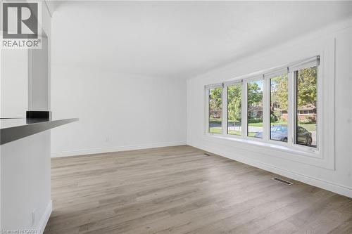 Wood-finish flooring, white painted walls, multi-pane window with white trim, and a black countertop bar - 49 Beverly Crescent, Welland, ON 