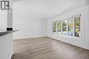 Wood-finish flooring, white painted walls, multi-pane window with white trim, and a black countertop bar - 49 Beverly Crescent, Welland, ON 
