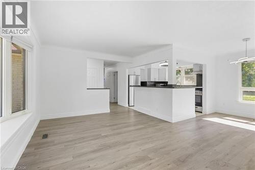 Open concept living area featuring wood-finish flooring, white walls, and a large bay window - 49 Beverly Crescent, Welland, ON 