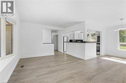Open concept living area featuring wood-finish flooring, white walls, and a large bay window - 