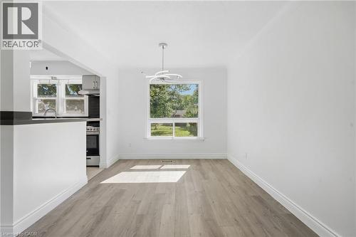Open concept floorplan featuring a contemporary light fixture, large window, and wood-finish flooring - 49 Beverly Crescent, Welland, ON 