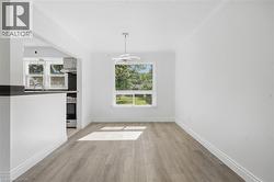 Open concept floorplan featuring a contemporary light fixture, large window, and wood-finish flooring - 