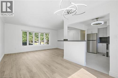 Open concept living space featuring wood-finish flooring, a contemporary chandelier, a bay window, a breakfast bar, and stainless steel appliances - 49 Beverly Crescent, Welland, ON 