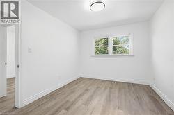 White walls, wood-finish flooring, and a flush-mount ceiling light - 