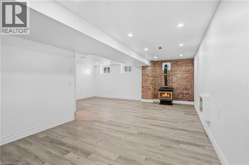 Spacious room with wood-finish flooring, recessed lighting, and an exposed brick accent wall - 49 Beverly Crescent, Welland, ON 