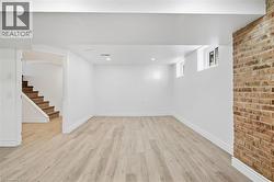 Finished lower level with wood-finish flooring, recessed lighting, and exposed brick accent wall - 