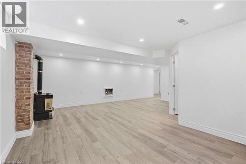 Wood-finish flooring, recessed lighting, brick-clad column, built-in fireplace, and a wood-burning stove - 49 Beverly Crescent, Welland, ON 