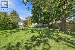 Expansive grassy yard with mature trees, a wood privacy fence, and rear exterior building elements - 