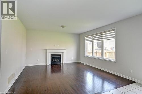 Hardwood-style flooring, white trim, recessed fireplace, white mantel, and large window with blinds - 236 Ridge Road, Cambridge, ON 