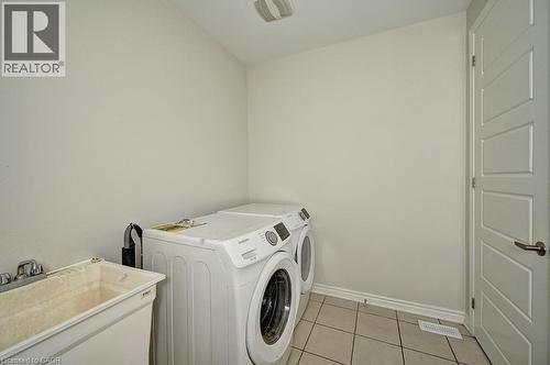 Utility sink with chrome faucet, light tile flooring, and a paneled door - 236 Ridge Road, Cambridge, ON 