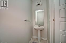 Pedestal sink with chrome faucet, wall-mounted mirror, and overhead vanity lighting - 
