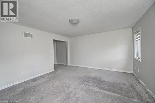 Neutral wall paint, ceiling-mounted light fixture, light gray carpet flooring, and white trim - 236 Ridge Road, Cambridge, ON 