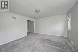 Neutral wall paint, ceiling-mounted light fixture, light gray carpet flooring, and white trim - 