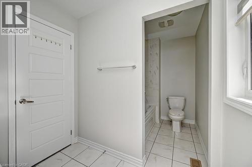 White panel door, chrome towel bar, white tile flooring, white window trim, and a built-in toilet - 236 Ridge Road, Cambridge, ON 